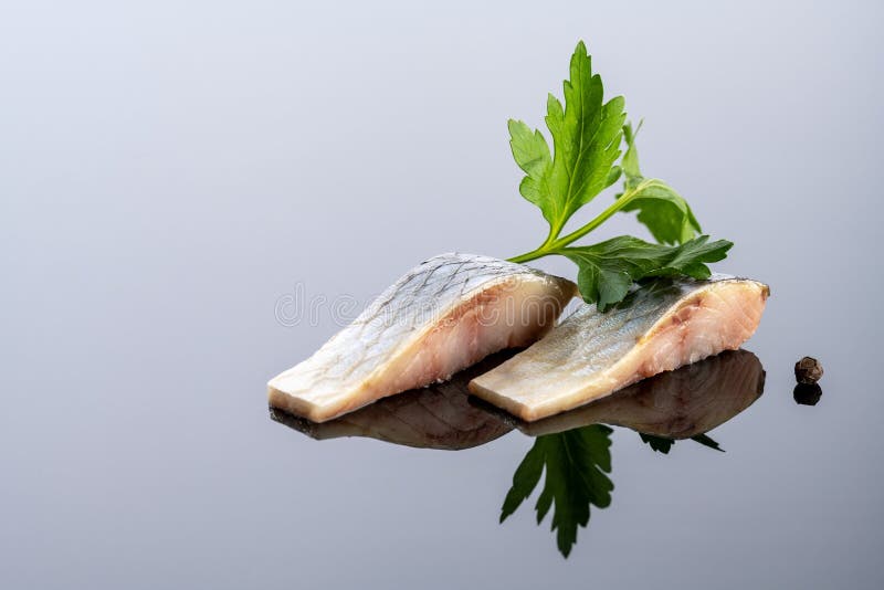 Pieces of Salted Herring Fish on a Mirror Background Stock Photo