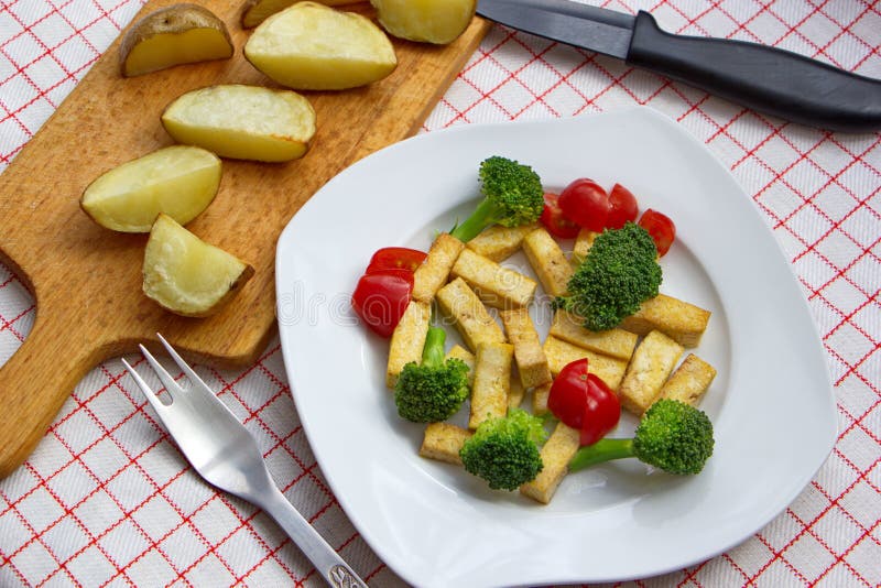 Pieces of Tofu Served with Broccoli, Tomatoes and Baked Potatoes Stock