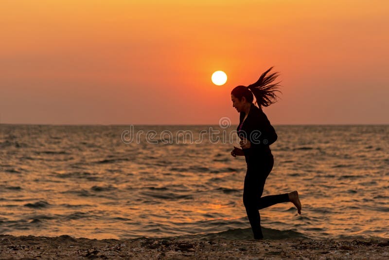 Piedi del corridore della siluetta che corrono sulla spiaggia nel tramonto all'aperto Forma fisica asiatica e essere in corsa per fotografia stock libera da diritti Piedi del corridore della siluetta che corrono sulla spiaggia nel tramonto all'aperto Forma fisica asiatica e essere in corsa per fotografia stock libera da diritti
