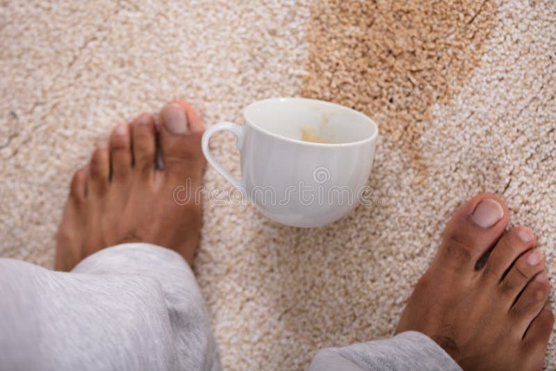 Piedi del ` s della persona che stanno vicino al caffè rovesciato fotografie stock Piedi del ` s della persona che stanno vicino al caffè rovesciato fotografie stock