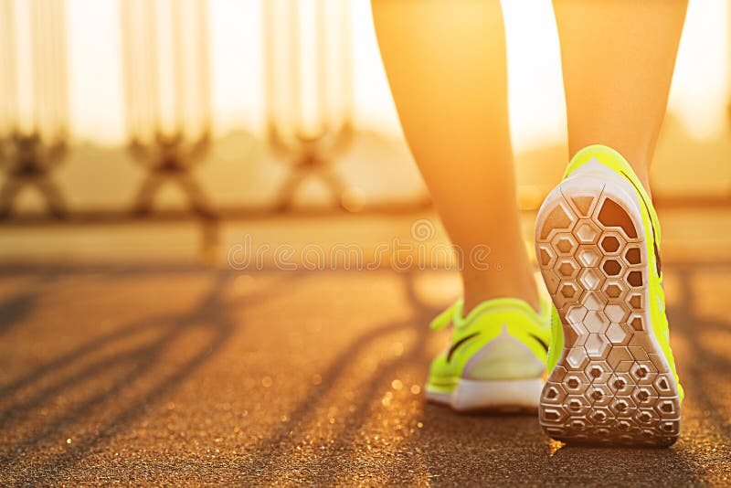 Piedi della donna del corridore che corrono sul primo piano della strada sulla scarpa Fitnes femminili Piedi della donna del corridore che corrono sul primo piano della strada sulla scarpa Fitnes femminili