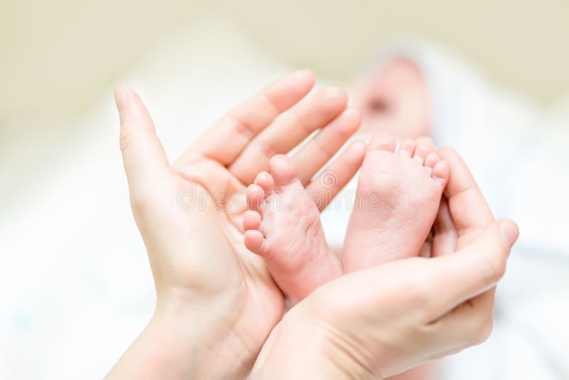 Piedi della holding della madre del bambino appena nato Gambe infantili in mano del genitore Assegno familiare per i figli e cura