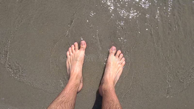 Piedi nudi dell'uomo sulla spiaggia di adriatica lavata via acqua