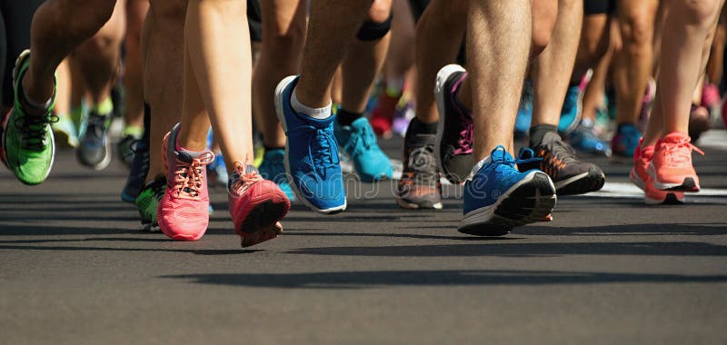Pieds courants de personnes de course de marathon sur la route urbaine