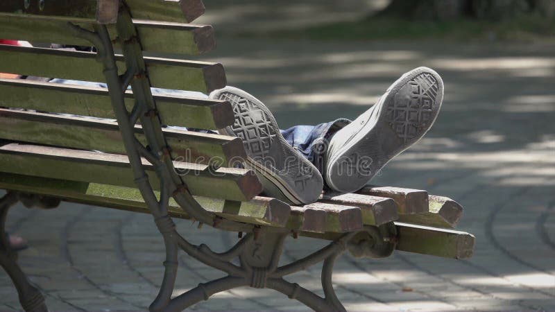 Pieds d'une personne dormant en parc public