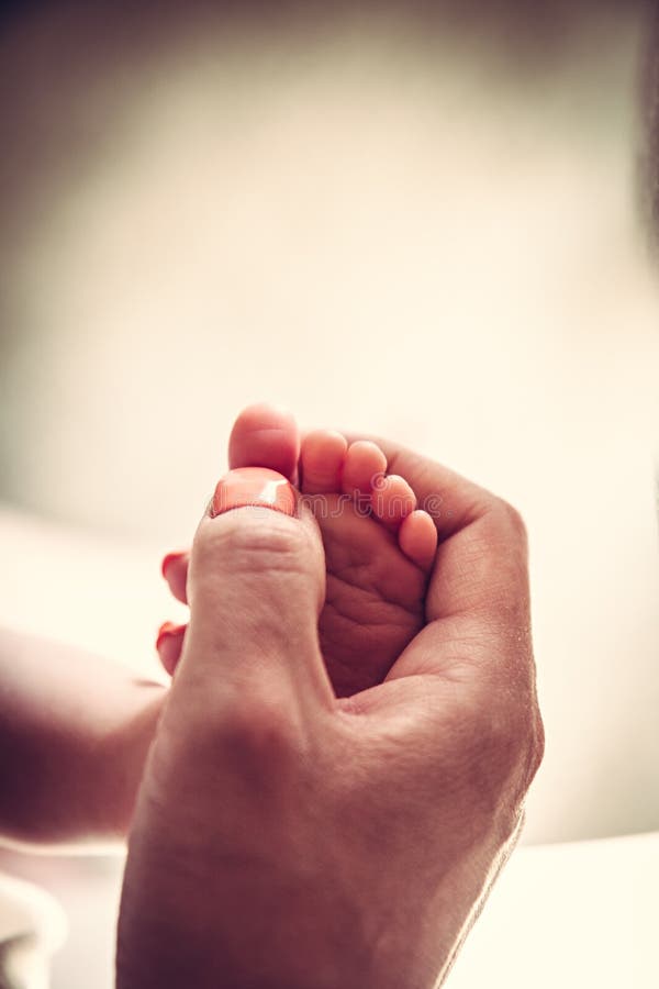 Pieds de bébé dans les mains de mère photographie stock libre de droits Pieds de bébé dans les mains de mère photographie stock libre de droits