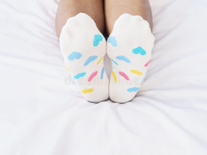 Pieds de femme portant la chaussette blanche avec le modèle en pastel de forme de coeur photos stock Pieds de femme portant la chaussette blanche avec le modèle en pastel de forme de coeur photos stock