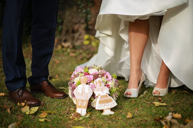 Pieds de jeunes mariés avec le bouquet de mariage et le gingerbrea de mariage image stock Pieds de jeunes mariés avec le bouquet de mariage et le gingerbrea de mariage image stock