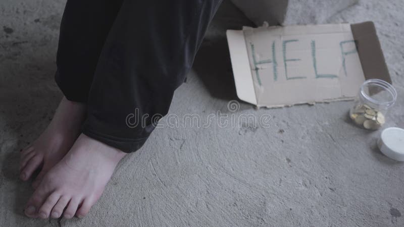 Pieds de la pauvre fille aux pieds nus non reconnue s'asseyant dans un vide poussiéreux dans le bâtiment abandonné Un signe qui i