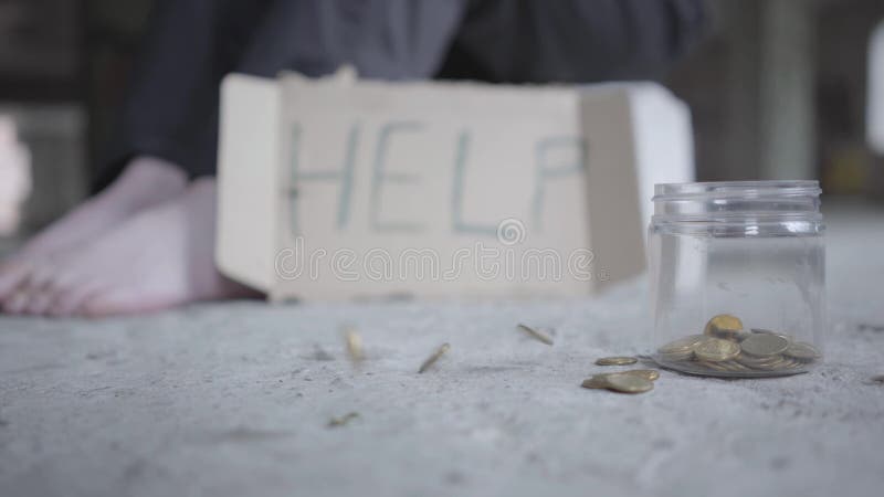 Pieds de pauvre fille aux pieds nus sur le plan rapproché concret de plancher Un signe brouillé qui indique l'aide est près Pièce