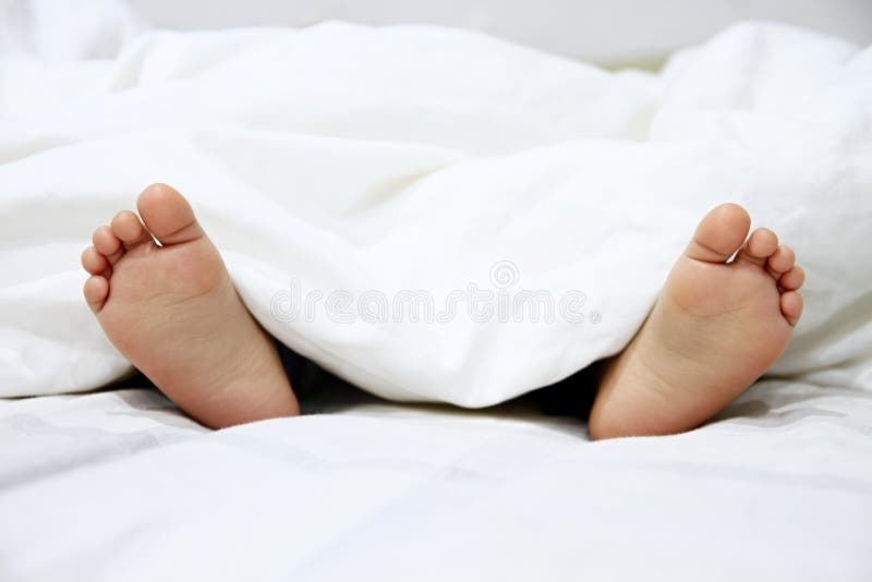 Pieds de petits garçons dans le lit photographie stock Pieds de petits garçons dans le lit photographie stock