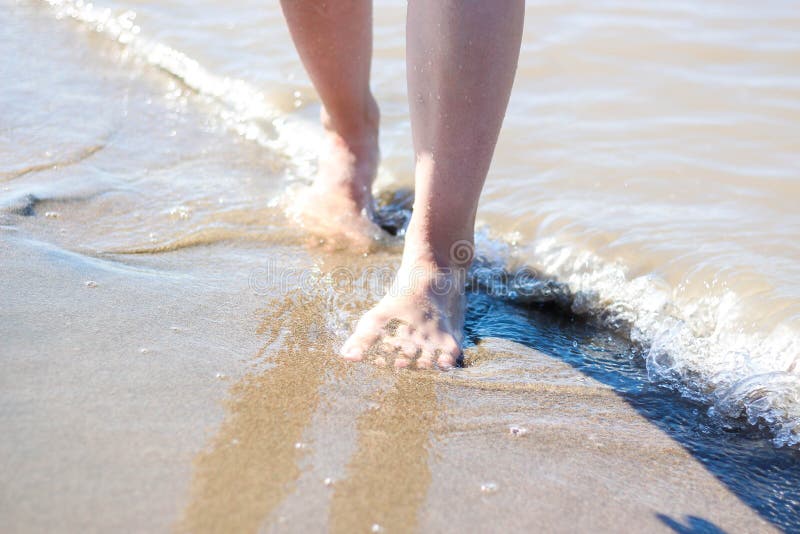 Pieds du ` s de fille sur la plage Vagues et jambes de mer photo libre de droits Pieds du ` s de fille sur la plage Vagues et jambes de mer photo libre de droits