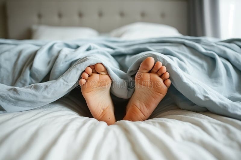 Cozy morning scene with person&#x27;s bare feet poking out from soft blue bed covers AI generated. Cozy morning scene with person&#x27;s bare feet poking out from soft blue bed covers AI generated