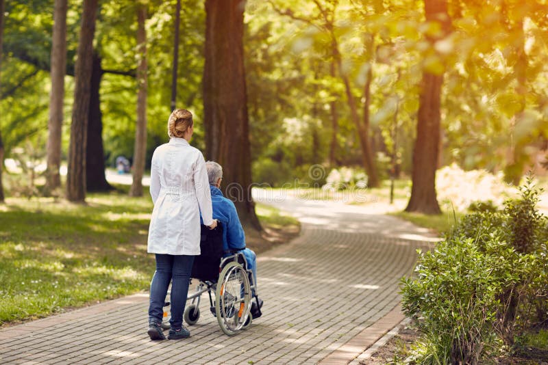 Pielęgniarek starszych osob pomaga mężczyzna na wózku inwalidzkim plenerowym