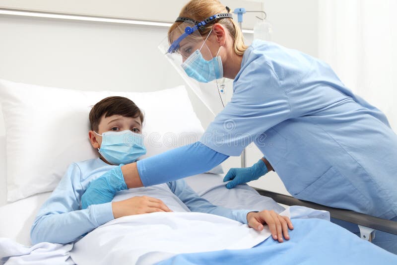 Nurse takes care of the patient child in hospital bed, wearing protective masks, corona virus covid 19 protection concept. Nurse takes care of the patient child in hospital bed, wearing protective masks, corona virus covid 19 protection concept.