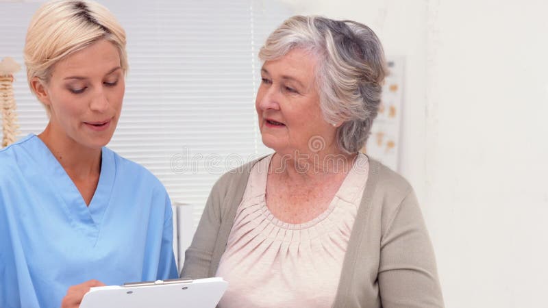 Pielęgniarka opowiada z starszym pacjentem w biurze