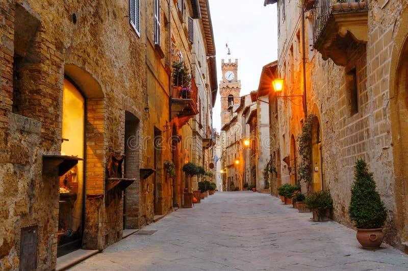 Pienza, Τοσκάνη, Ιταλία - αρχαία οδός με τα κτήρια πετρών, στο υπόβαθρο ο πύργος κουδουνιών αιθουσών πόλεων στοκ φωτογραφία με δικαίωμα ελεύθερης χρήσης Pienza, Τοσκάνη, Ιταλία - αρχαία οδός με τα κτήρια πετρών, στο υπόβαθρο ο πύργος κουδουνιών αιθουσών πόλεων στοκ φωτογραφία με δικαίωμα ελεύθερης χρήσης