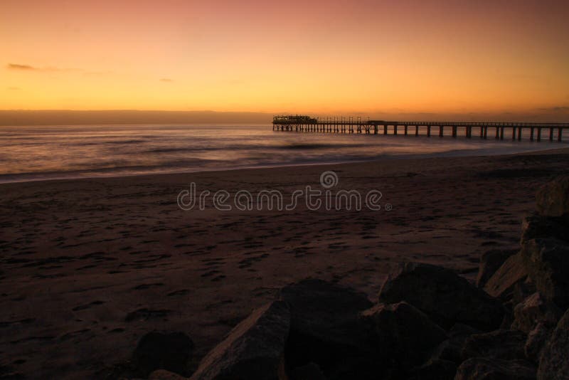 Pier on the Atlantic Ocean in Swakompund, Namibia. Beautiful sunset with a bright sky and soft gentle water