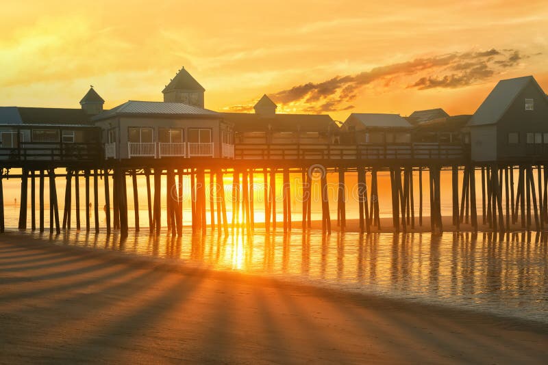 Pier in fog and golden sun at dawn. A famous place on the coast of the Atlantic Ocean. Old pier. USA. Maine.