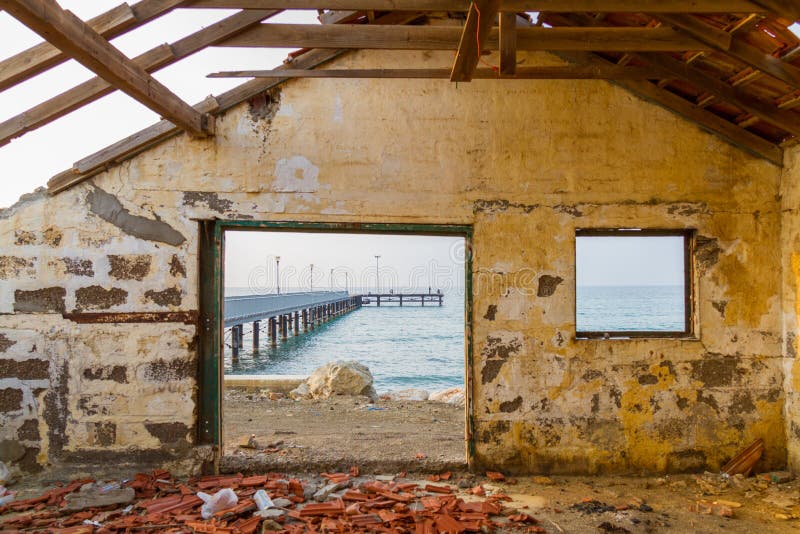 Pieransicht durch aufgegebenes Hausfenster durch den Strand lizenzfreie stockfotografie Pieransicht durch aufgegebenes Hausfenster durch den Strand lizenzfreie stockfotografie