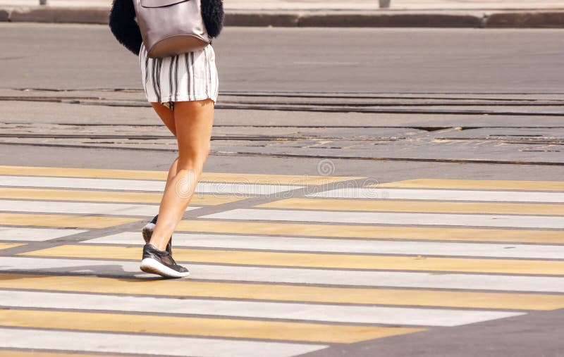 Piernas del ` s de la mujer joven que cruzan una calle urbana imágenes de archivo libres de regalías Piernas del ` s de la mujer joven que cruzan una calle urbana imágenes de archivo libres de regalías