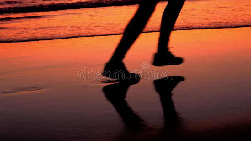 Piernas femeninas trotando en la playa de arena