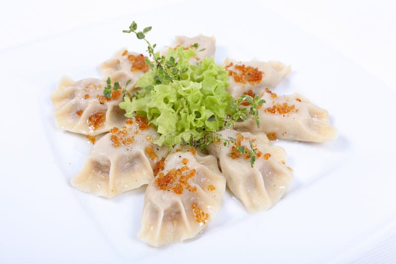 assiette contenant quelques pierogi, ces délicieux raviolis polonais, accompagnés d'une feuille de salade