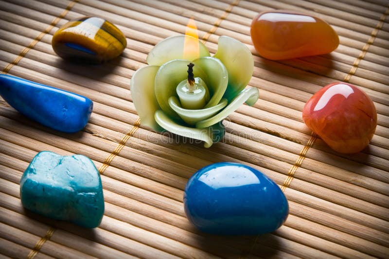 Healing stones in circle with beautiful candle in form of flower on bamboo like a concept for alternative medicine or wellness. Healing stones in circle with beautiful candle in form of flower on bamboo like a concept for alternative medicine or wellness