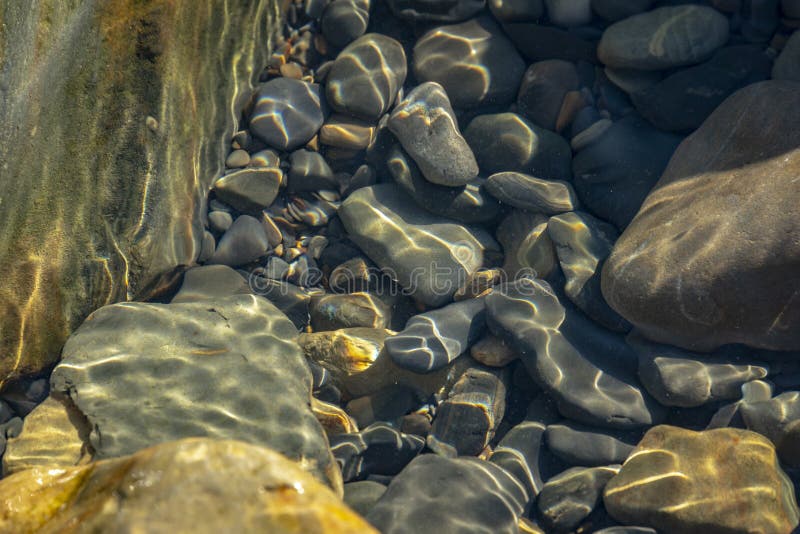 Sea stones and rocks of different sizes and texsture of black, gray and brown under the water on the Black Sea coast as nature bacground. Excellent concept for any design. Sea stones and rocks of different sizes and texsture of black, gray and brown under the water on the Black Sea coast as nature bacground. Excellent concept for any design