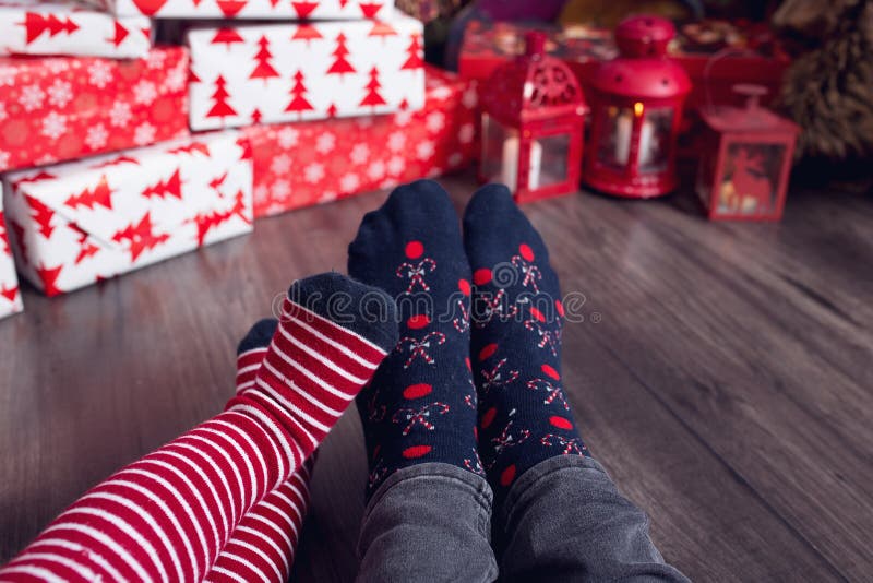 Pies con calcetines de navidad en plaid. madre e hijo sentados juntos y preparando regalos. gente relajándose en casa