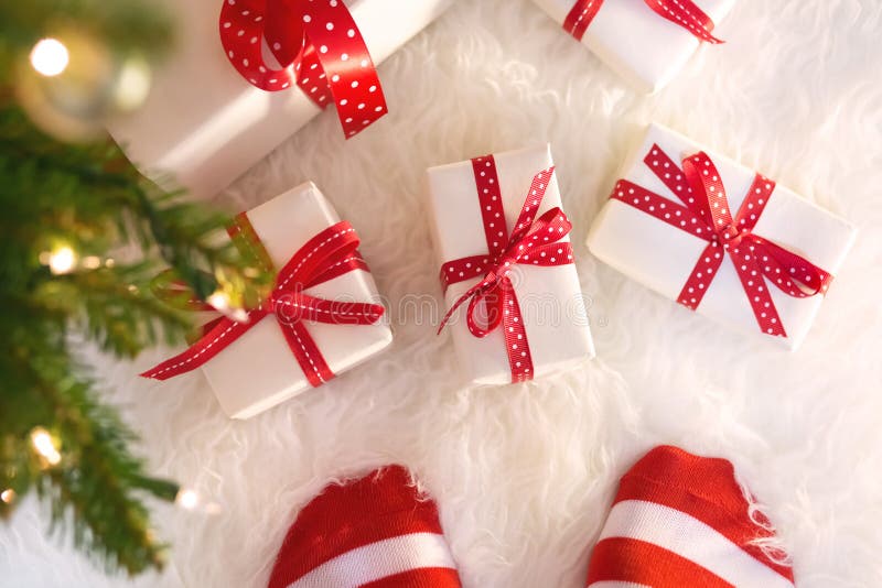 Feet with striped socks with Christmas gift boxes on white carpet. Feet with striped socks with Christmas gift boxes on white carpet