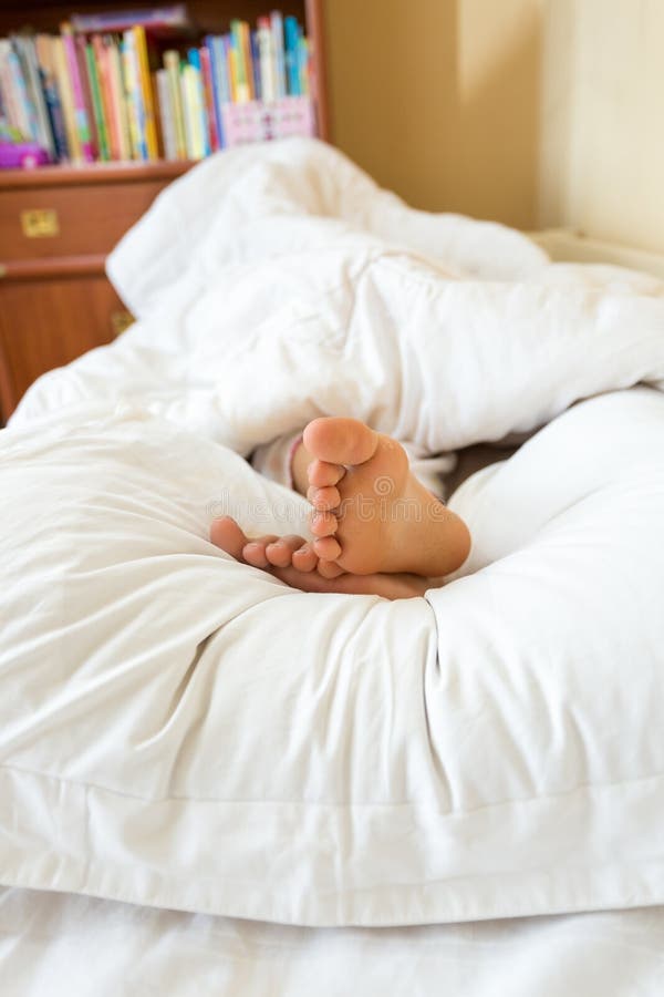 Closeup view of girls feet lying on white pillow at bedroom. Closeup view of girls feet lying on white pillow at bedroom
