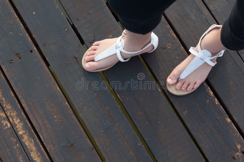 Pies de las niñas en las sandalias blancas
