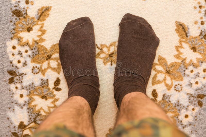 Closeup photo of male feet with brown woolen socks standing on carpet. Closeup photo of male feet with brown woolen socks standing on carpet