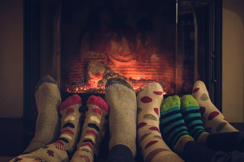 Feet in socks of all the family relaxing and warming by cozy fire. Feet in socks of all the family relaxing and warming by cozy fire