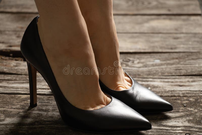Pies Femeninos En Cuero Negro Zapatos De Tacón Alto Zapatos De Piso De Madera Vieja Foto de archivo - Imagen de género, dolor: