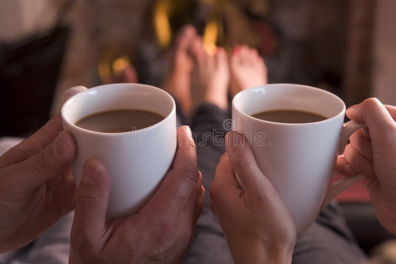 Pies que se calientan en la chimenea con café fotografía de archivo libre de regalías