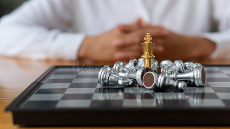 Piesele de șah ale reginei de aur sunt înconjurate de o grămadă de piese de șah de argint pe tablă. șahul regelui plasat în centru stock photos