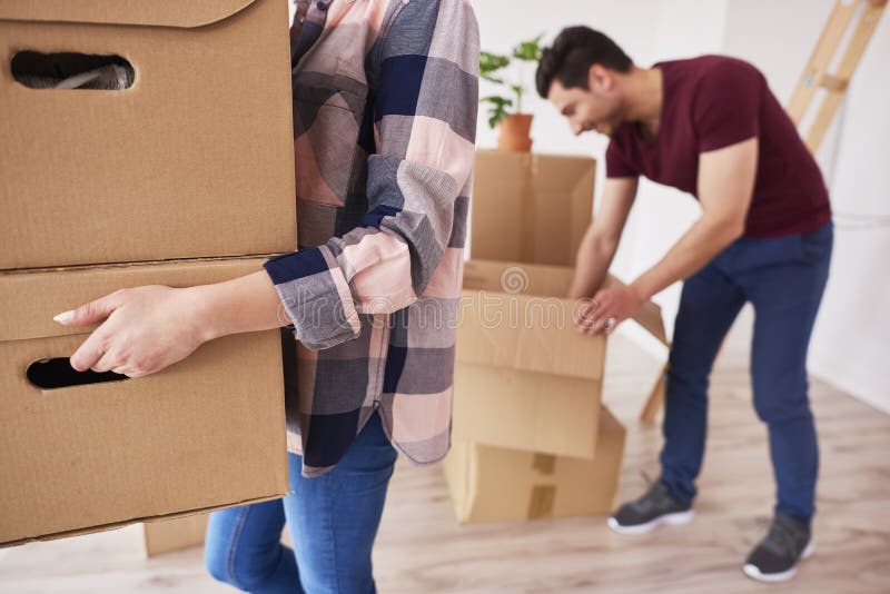 Pieza de cajas de cartón de la mujer que llevan en el nuevo apartamento imagen de archivo Pieza de cajas de cartón de la mujer que llevan en el nuevo apartamento imagen de archivo