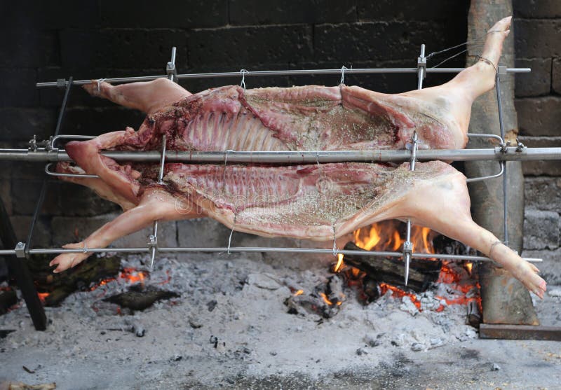 pig on the spit and slowly cooked on the large fireplace during stock photo pig on the spit and slowly cooked on the large fireplace during stock photo