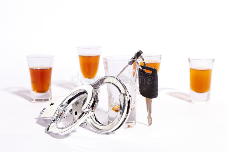 A still life of shot glasses, car keys and police handcuffs against a white background. A still life of shot glasses, car keys and police handcuffs against a white background.