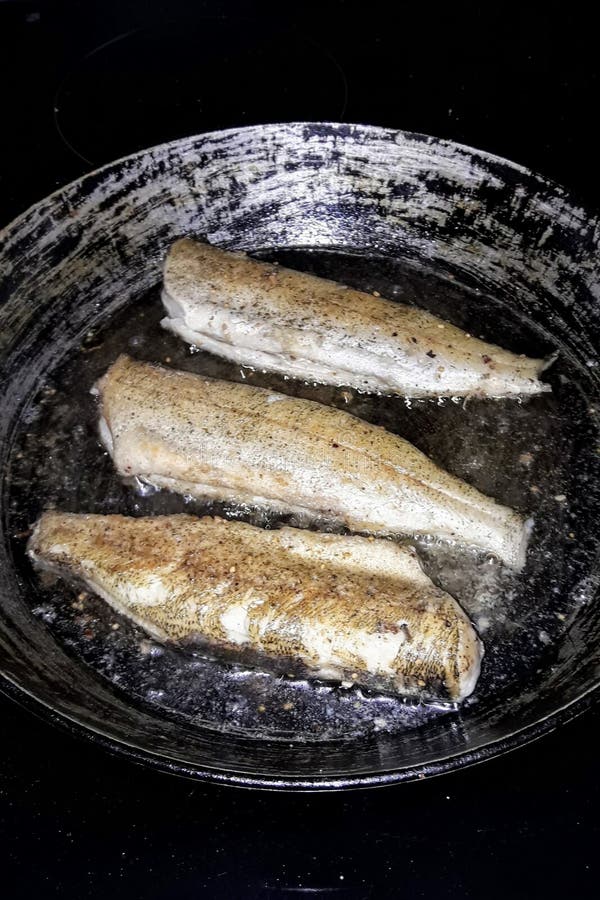 Pike Fish without Head and Tail is Fried in an Old Castiron Skillet