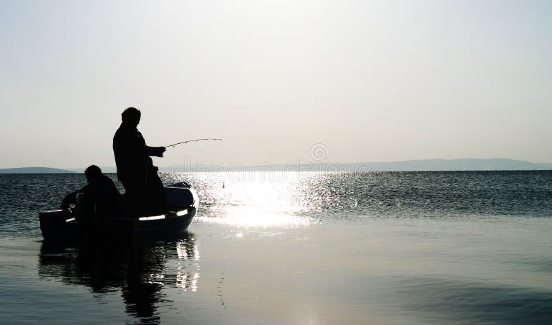 Two lonely fishermen pike fishing at dusk, on a big lake, in the Danube Delta