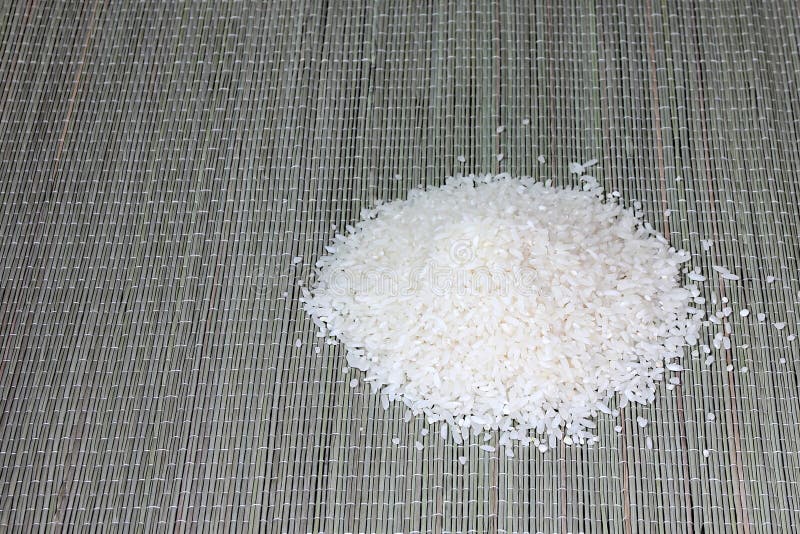 Pila de arroz echada en una alfombra. Arroz blanco vertido en un tobogán sobre una alfombra de arroz de paja