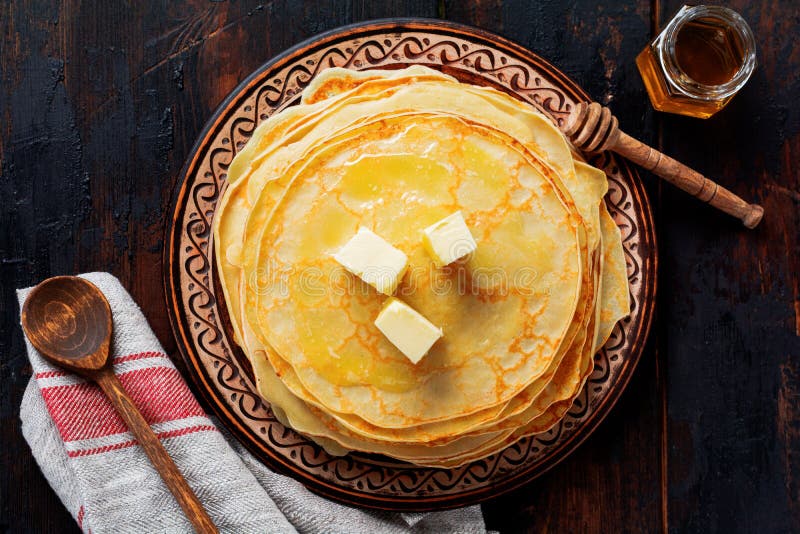 Pila de crepes finas hechas en casa con los pedazos de mantequilla, de leche y de miel en la placa de cer?mica r?stica vieja imagen de archivo libre de regalías Pila de crepes finas hechas en casa con los pedazos de mantequilla, de leche y de miel en la placa de cer?mica r?stica vieja imagen de archivo libre de regalías