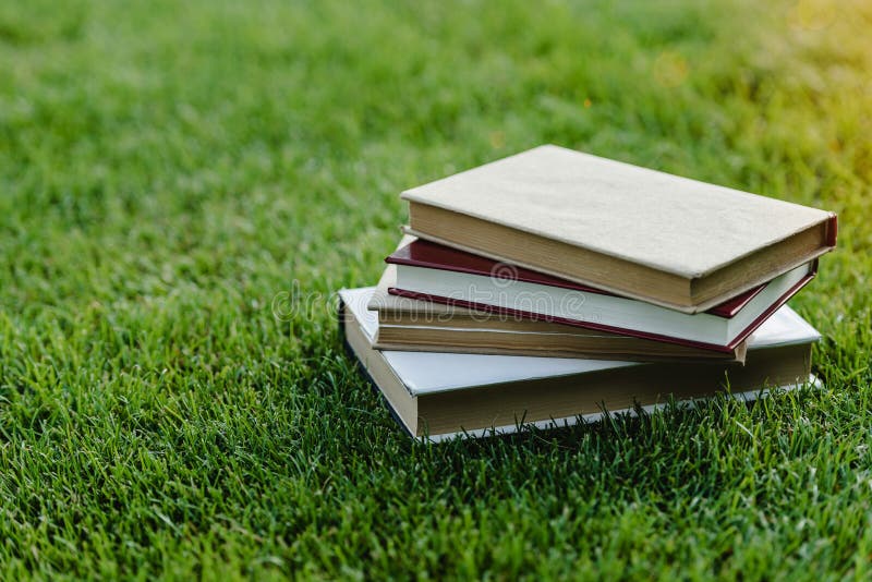 Pila de libros en hierba verde en la puesta del sol imagen de archivo Pila de libros en hierba verde en la puesta del sol imagen de archivo