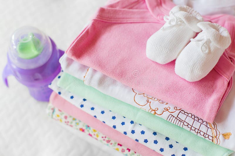 Pila di abbigliamento del bambino con un biberon fotografie stock libere da diritti Pila di abbigliamento del bambino con un biberon fotografie stock libere da diritti
