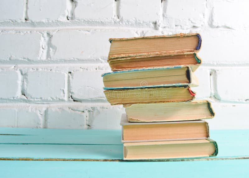 Pila di libri antichi sulla tavola contro un muro di mattoni bianco Concetto della scuola, istruzione immagini stock Pila di libri antichi sulla tavola contro un muro di mattoni bianco Concetto della scuola, istruzione immagini stock