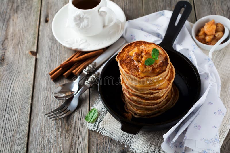 Pila di pancake da farina di grano saraceno con le mele al forno e la cannella su vecchio fondo di legno Una prima colazione sana immagini stock libere da diritti Pila di pancake da farina di grano saraceno con le mele al forno e la cannella su vecchio fondo di legno Una prima colazione sana immagini stock libere da diritti