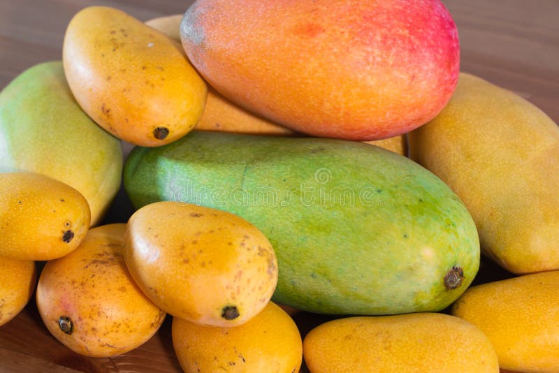 Pila di parecchie varietà di manghi della dimensione e dei colori differenti